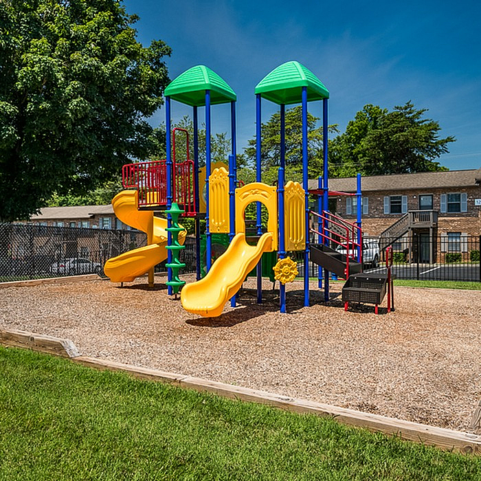 Vibrant outdoor playground with colorful slides and climbing structures, nestled in a charming residential setting.