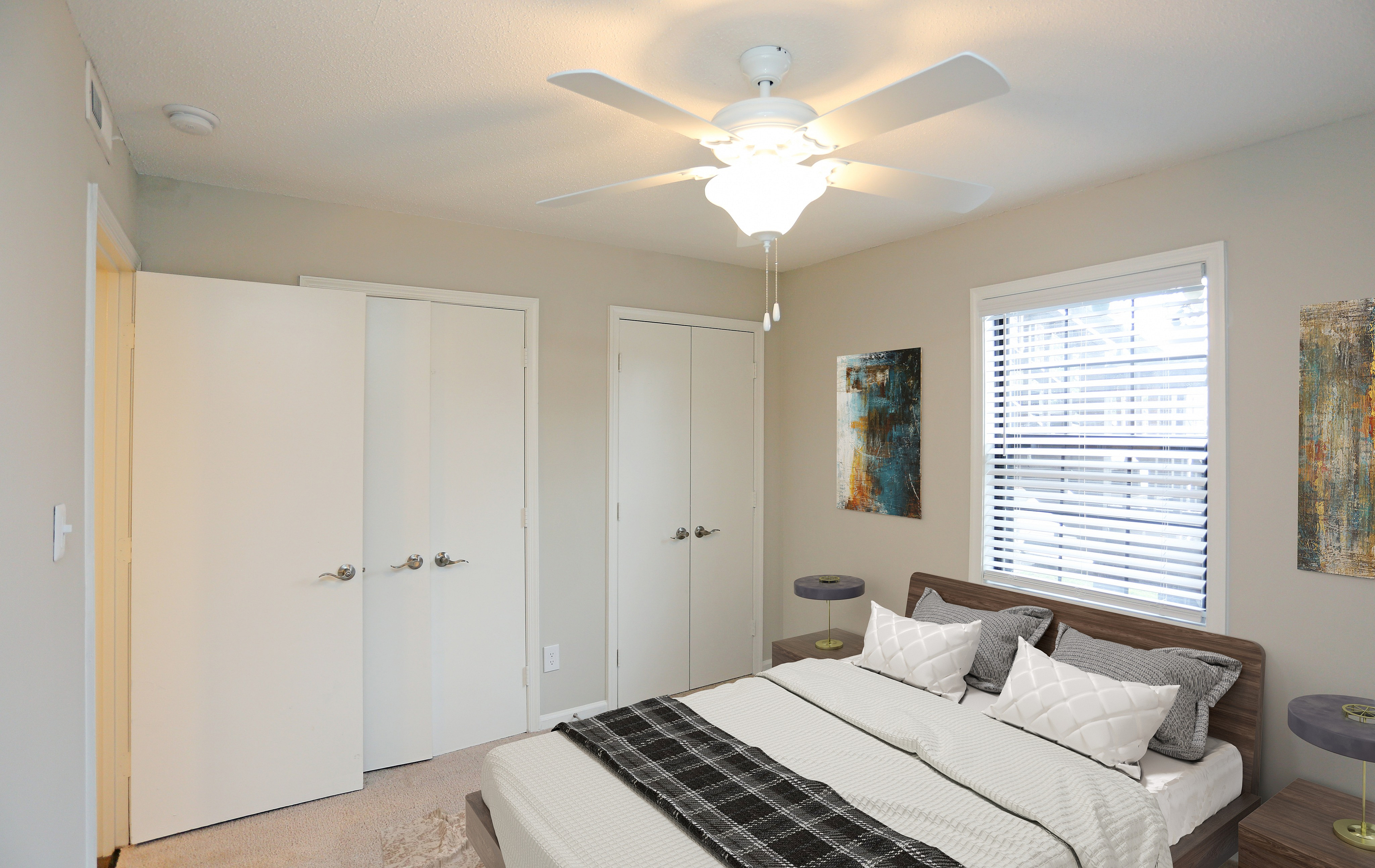 Inviting bedroom with modern decor, featuring a cozy bed, stylish artwork, and ample natural light through a large window.