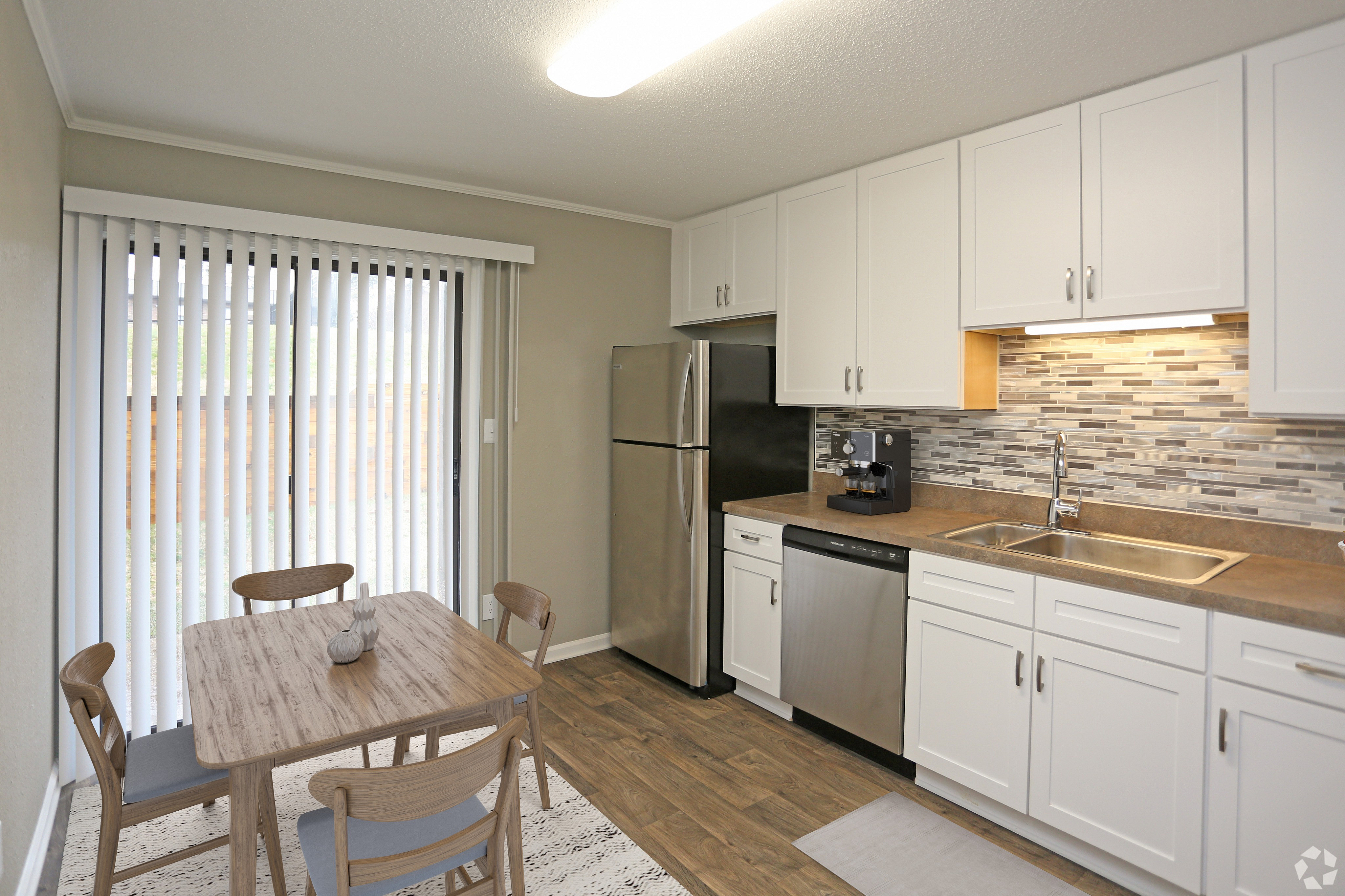 Bright and modern kitchen with sleek cabinets, stainless steel appliances, and a cozy dining area by large sliding glass doors.
