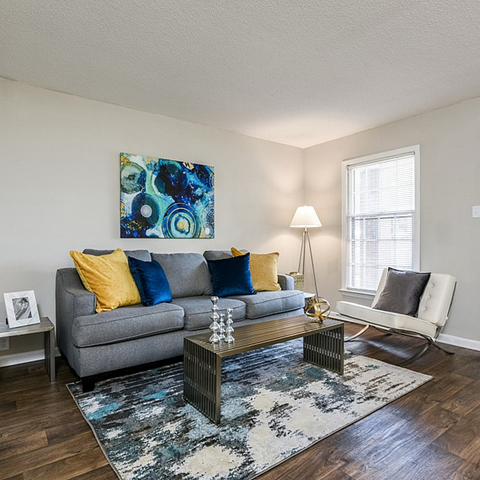 Inviting living room with modern decor, featuring a plush gray sofa, vibrant blue and yellow pillows, elegant artwork, and a stylish floor lamp.