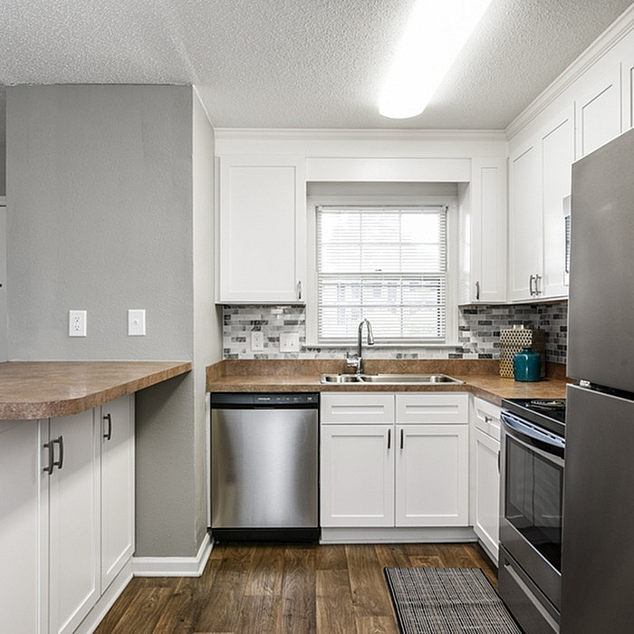 Bright and modern kitchen with sleek stainless steel appliances, elegant white cabinets, and a stylish tile backsplash.