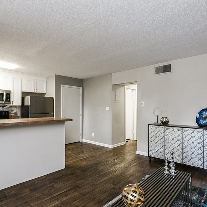 Modern open-concept living area with stylish decor and dark wood flooring, featuring a sleek kitchen with stainless steel appliances and elegant cabinetry.