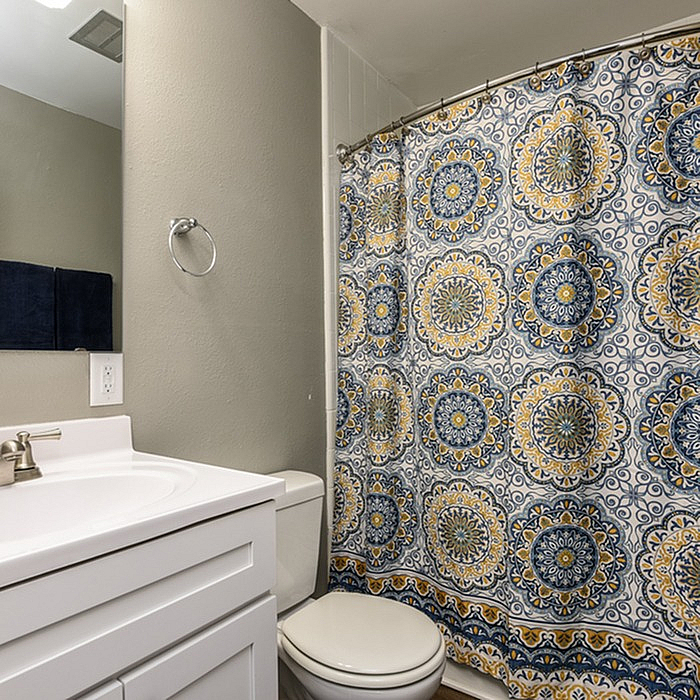 Chic bathroom with a stylish vanity and vibrant patterned shower curtain, offering a modern and inviting touch.