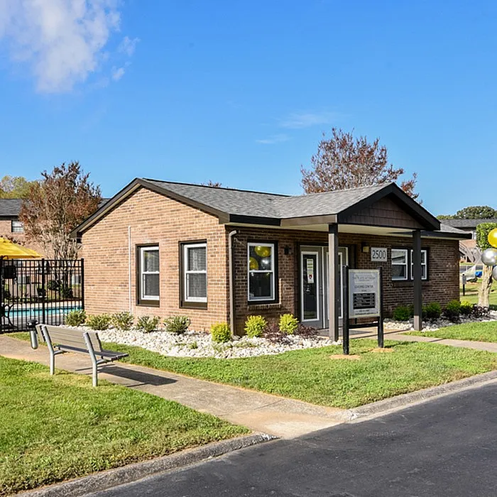 Charming brick office building surrounded by lush greenery and a vibrant pool area, ideal for community living.