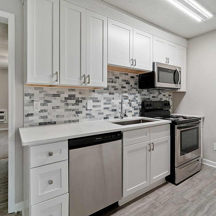 Modern kitchen with sleek white cabinetry, stainless steel appliances, and stylish tiled backsplash for a contemporary look.