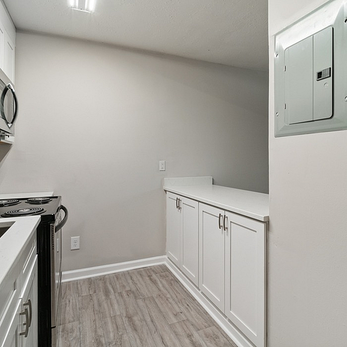 Modern kitchen featuring sleek white cabinetry, stainless steel appliances, and elegant laminate flooring.