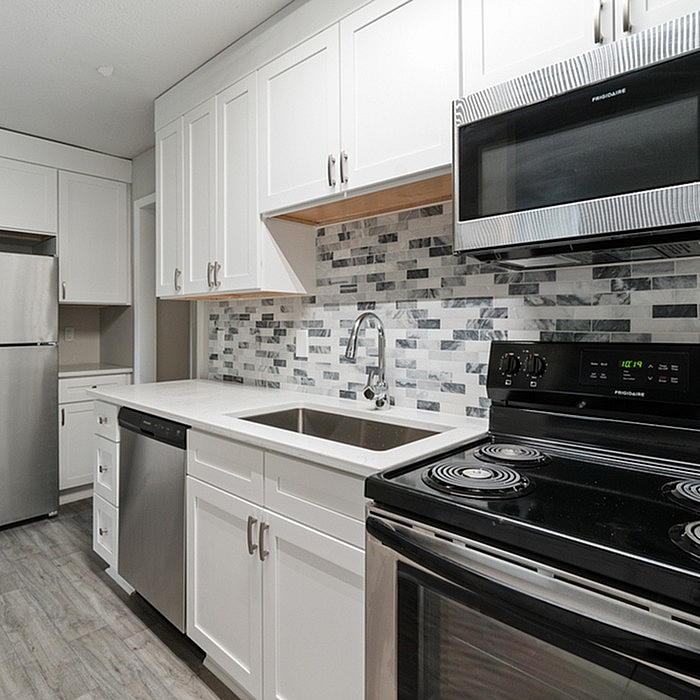 Modern kitchen with sleek stainless steel appliances, elegant white cabinetry, and stylish mosaic backsplash tiles.