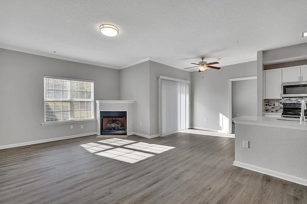 Bright and open living space with modern fireplace, sleek flooring, and a stylish kitchen making it the perfect cozy retreat.
