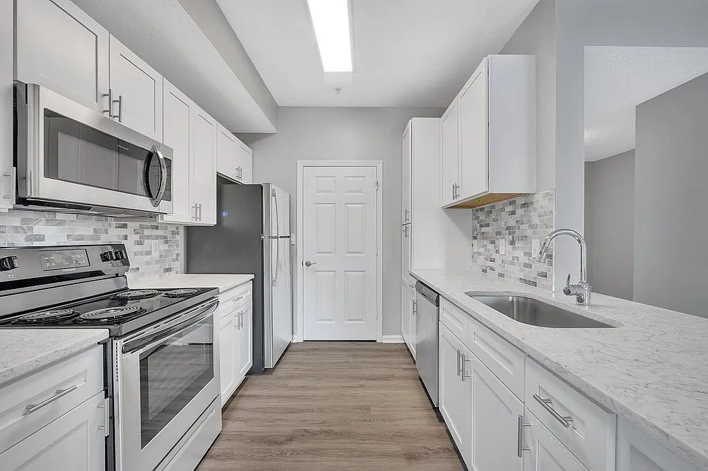 Sleek modern kitchen with white cabinetry, stainless steel appliances, and elegant marble countertops.