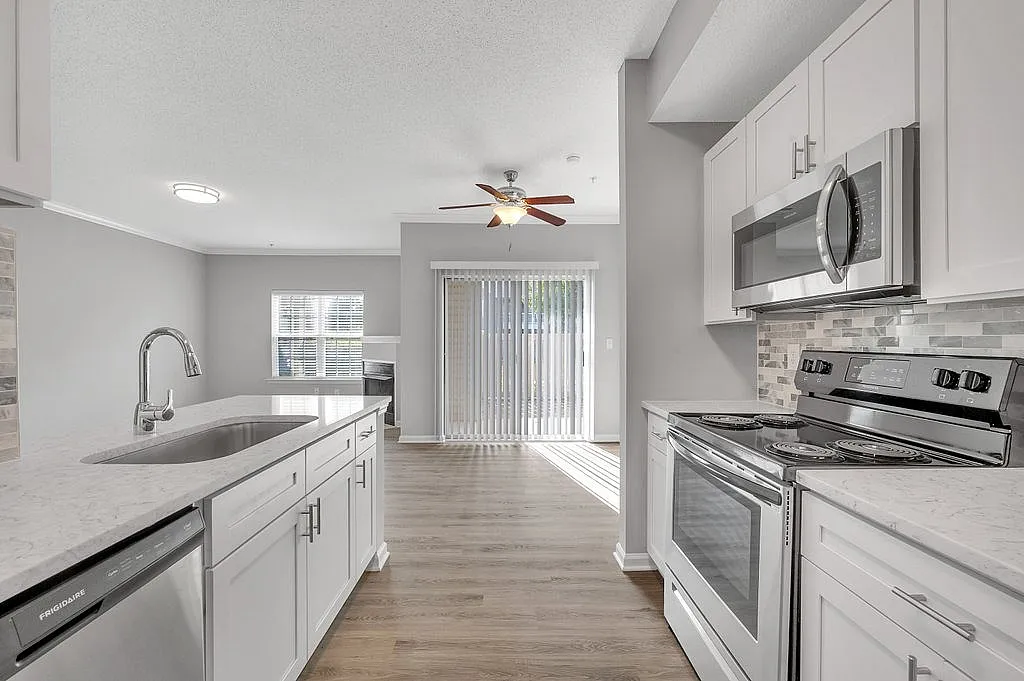 Modern kitchen with sleek appliances, elegant white cabinetry, and sunlit open-plan dining area.