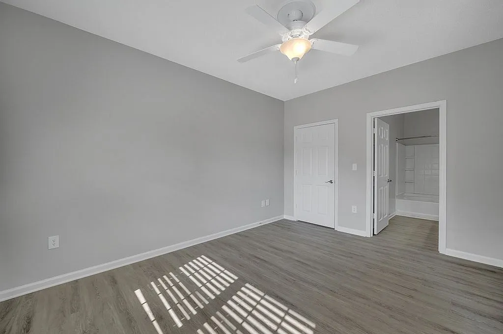 Bright and spacious bedroom with modern wood flooring and ceiling fan, featuring an en-suite bathroom for ultimate convenience.