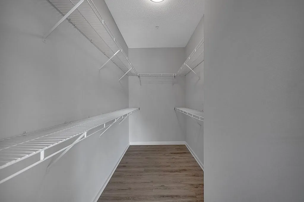 Spacious walk-in closet with elegant wire shelving and sleek hardwood floors, perfect for organized living.