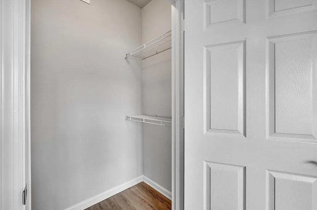 Bright and spacious walk-in closet with sleek shelving and elegant wooden flooring, perfect for organized storage.
