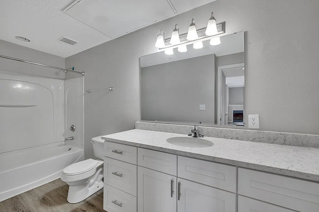 Modern bathroom with elegant white vanity, marble countertop, and bright overhead lighting, creating a sleek and inviting atmosphere.