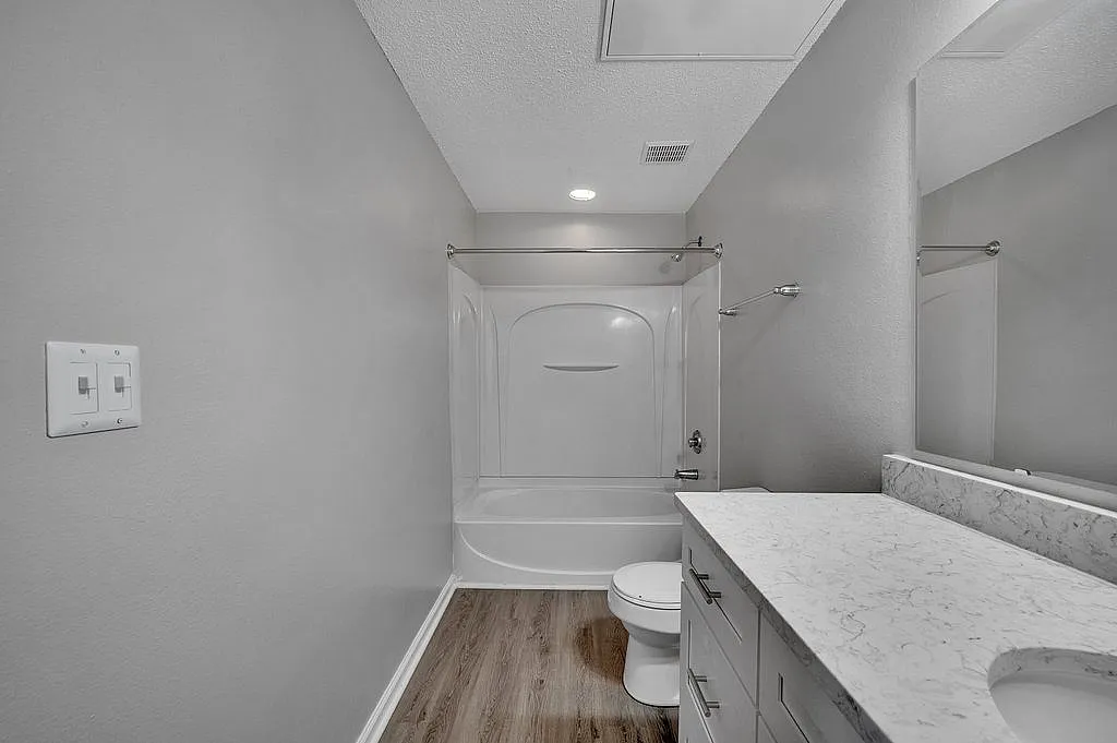 Elegant bathroom with modern fixtures, showcasing a pristine bathtub, sleek marble countertop, and stylish gray walls.