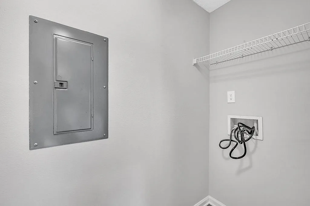 Bright utility area showcasing modern electrical panel and versatile shelving in a serene, minimalist setting.