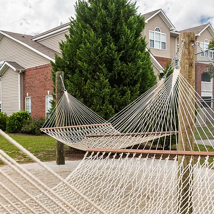 Relaxing communal area with inviting hammocks, lush greenery, and charming brick architecture.