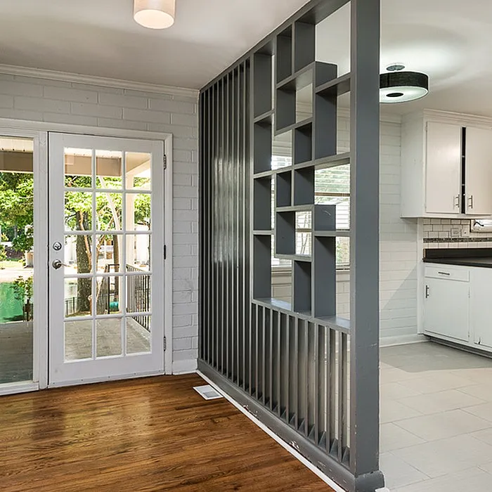 Inviting home interior featuring chic French doors, stylish partition, and a modern kitchen with elegant flooring.