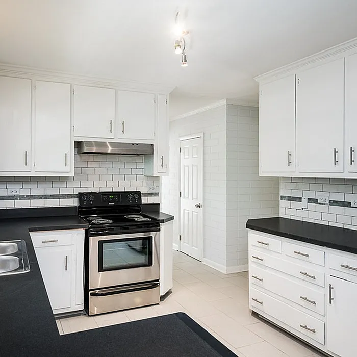 Modern kitchen with sleek white cabinetry, black countertops, and stainless steel appliances, ideal for culinary creativity.