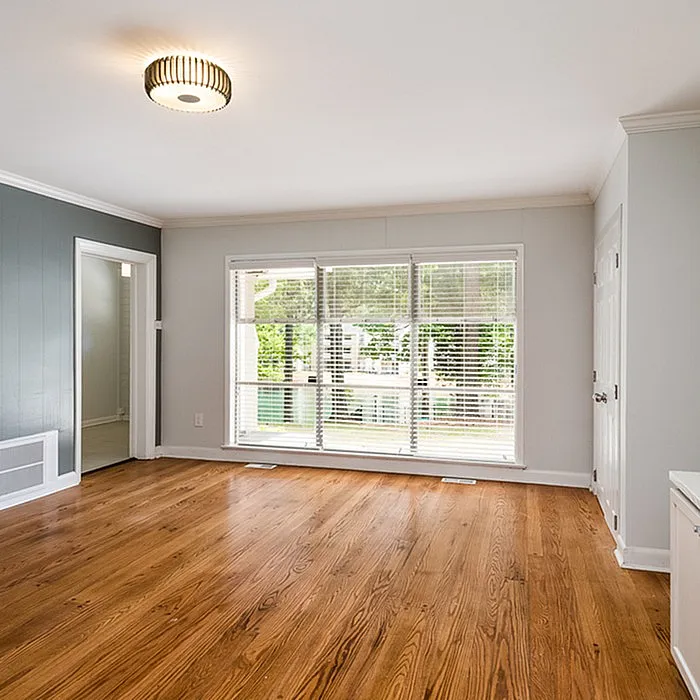 Bright and inviting living room with elegant hardwood flooring, large windows, and modern light fixture.