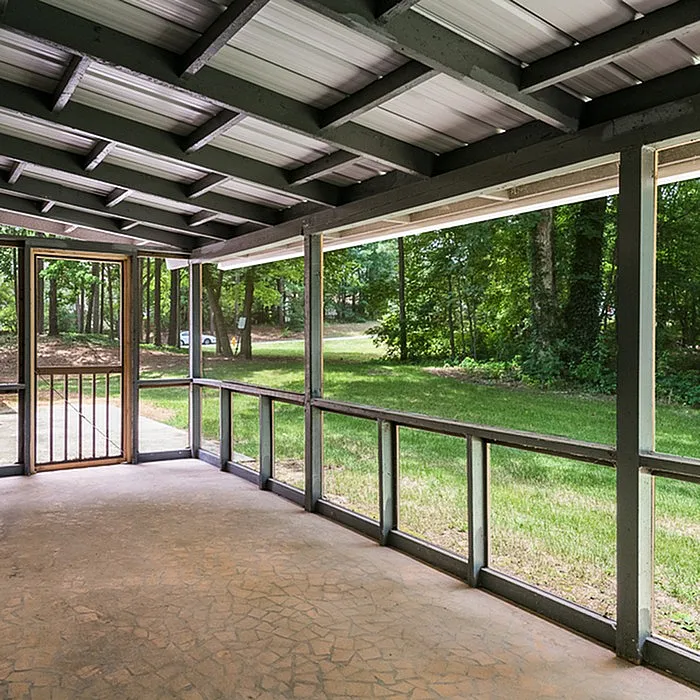 Charming screened porch with a picturesque view of lush green trees, perfect for relaxing and enjoying nature.