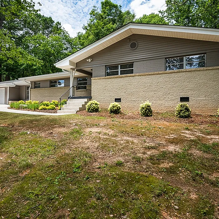 Charming single-story home with modern architecture, featuring a well-maintained front yard and surrounded by lush greenery for serene living.