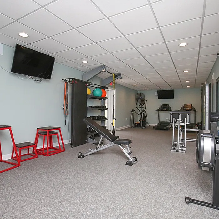 Modern fitness area with state-of-the-art equipment, featuring treadmills, weights, and aerobic steps in a sleek, well-lit space.