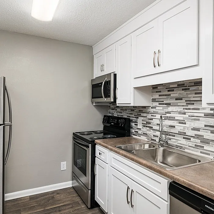 Modern kitchen with sleek stainless steel appliances, elegant backsplash, and white cabinetry offering ample storage space.