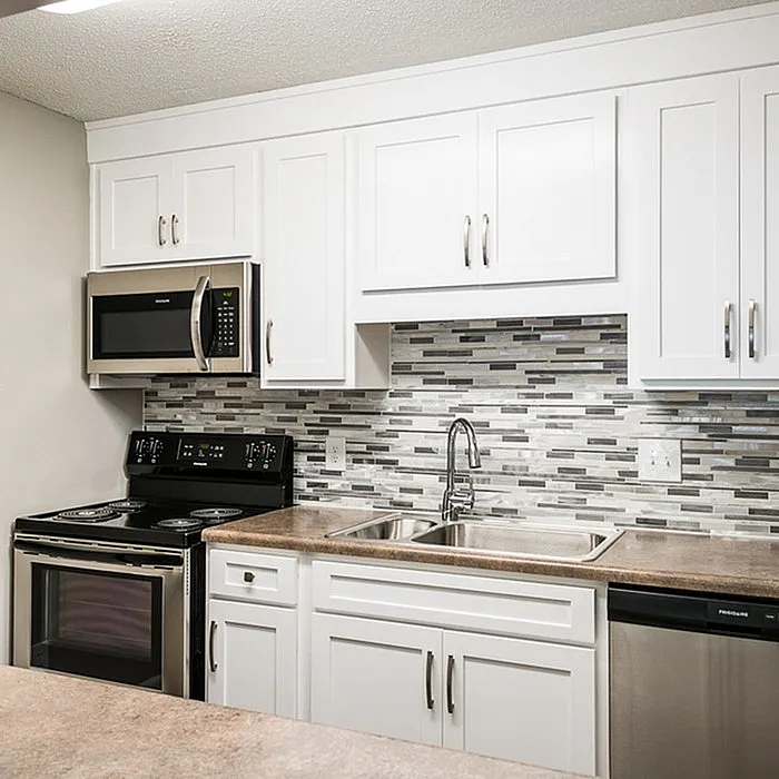 Modern kitchen with sleek white cabinetry, stylish backsplash, and stainless steel appliances including a microwave and dishwasher.