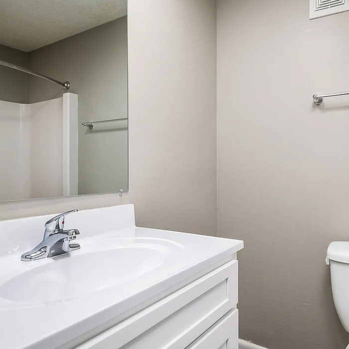 Modern bathroom with sleek white vanity, large mirror, and elegant fixtures, offering a fresh and clean aesthetic.