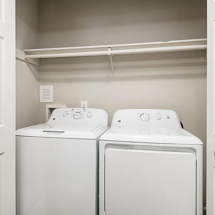 Modern laundry room featuring a sleek washing machine and dryer set with ample shelving for storage.