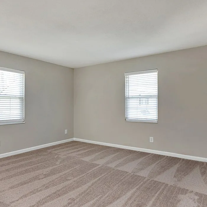 Bright and spacious bedroom with large windows and fresh, clean carpeting.