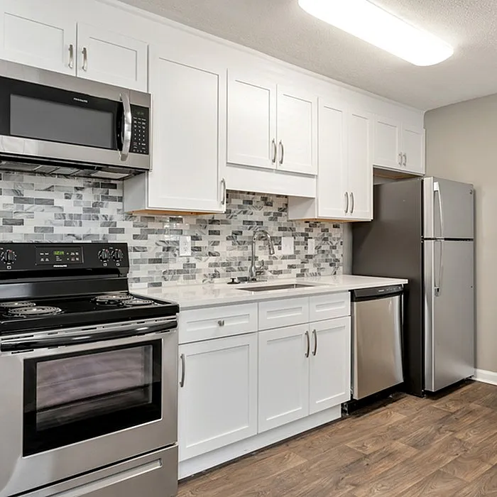 Modern kitchen with elegant white cabinetry, sleek stainless steel appliances, and stylish tiled backsplash.