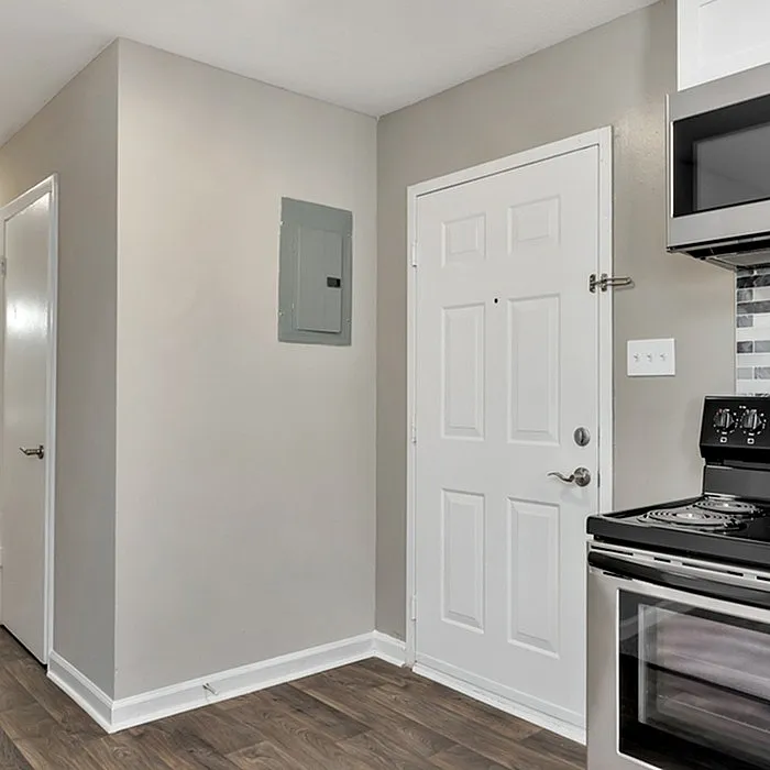 Inviting apartment entrance with warm hardwood floors, modern appliance setup, and sleek neutral walls.