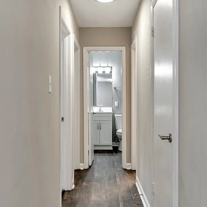 Bright hallway with elegant wood flooring leading to a modern bathroom featuring sleek fixtures.