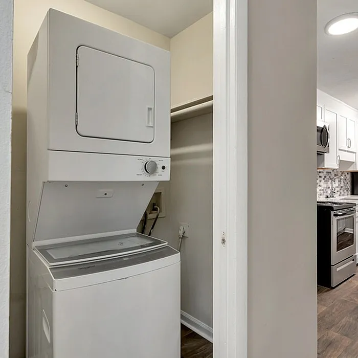 Convenient in-apartment laundry with modern stacked washer and dryer, near stylish kitchen with sleek appliances.