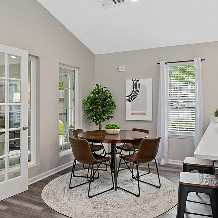 Bright dining area with elegant round table, contemporary chairs, and abundant natural light through French doors and large window, perfect for cozy gatherings.
