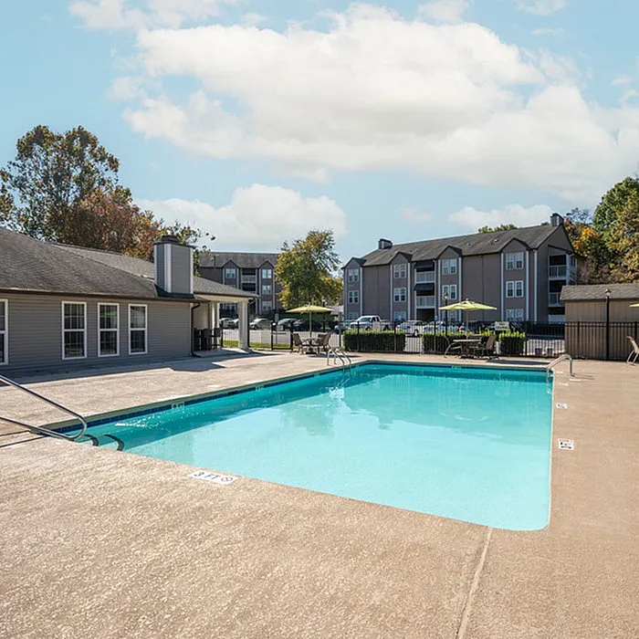 Inviting outdoor pool area with comfortable seating in a peaceful apartment complex, perfect for relaxation and sunny days.