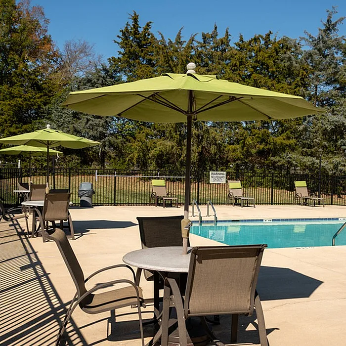 Inviting outdoor pool area with green umbrellas and comfortable seating, perfect for relaxation and leisure.