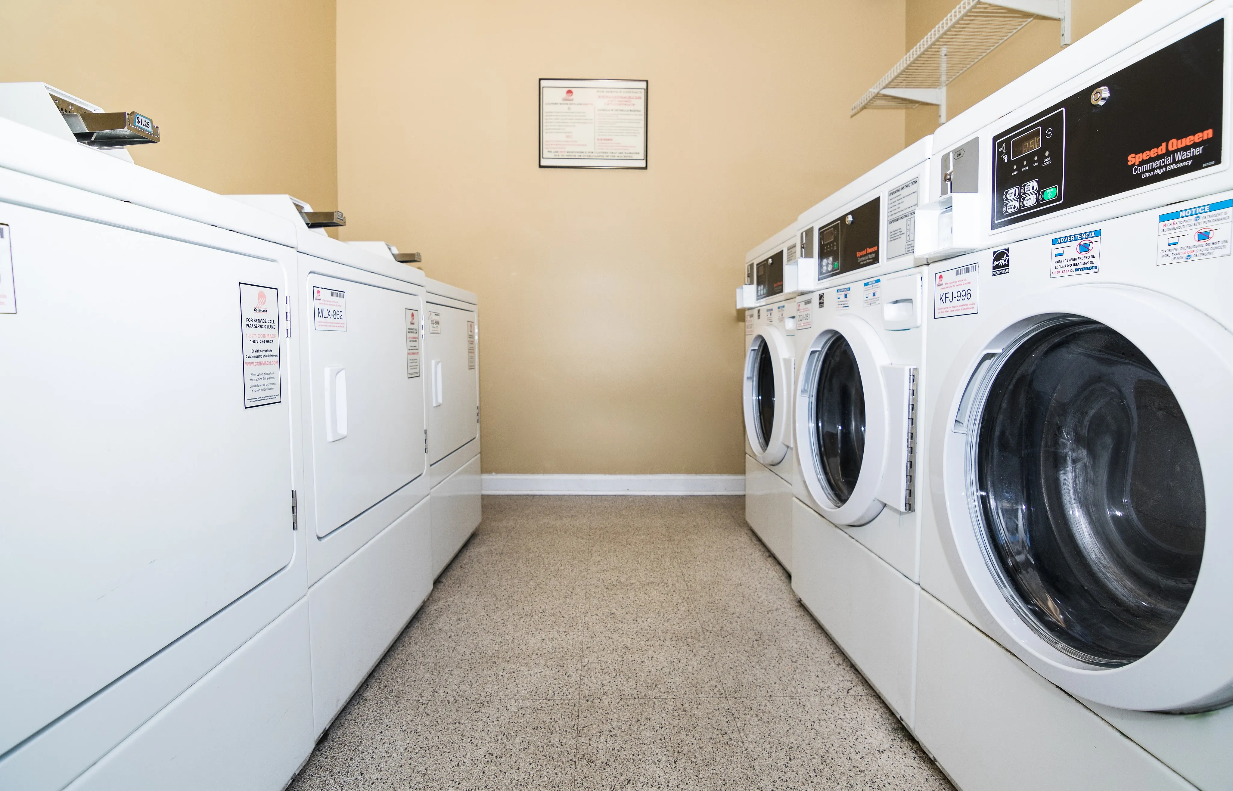 Bright and clean laundry room featuring modern washers and dryers, ideal for efficient and convenient living.