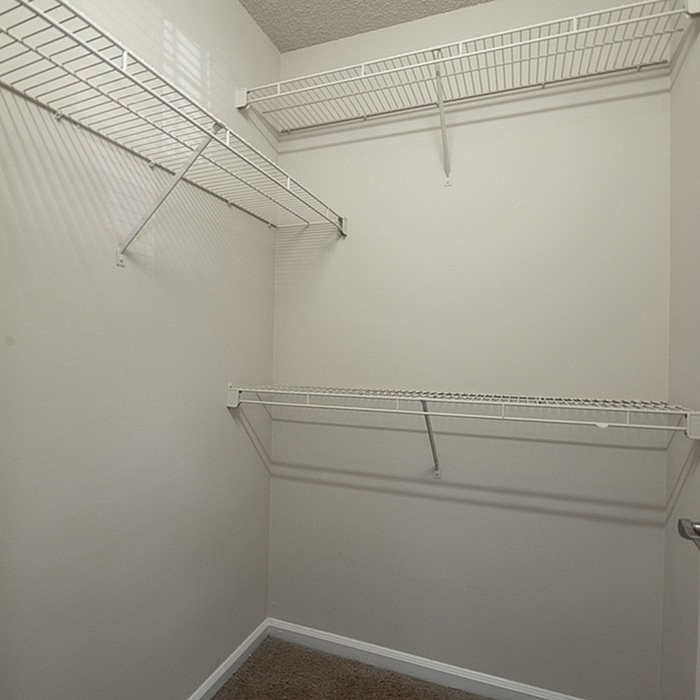 Spacious walk-in closet with sleek white wire shelving for organized storage solutions.