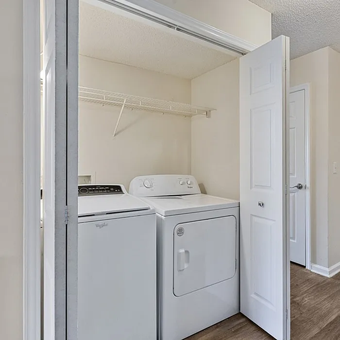 Chic laundry closet with modern washer and dryer, featuring an open shelf for convenient storage.