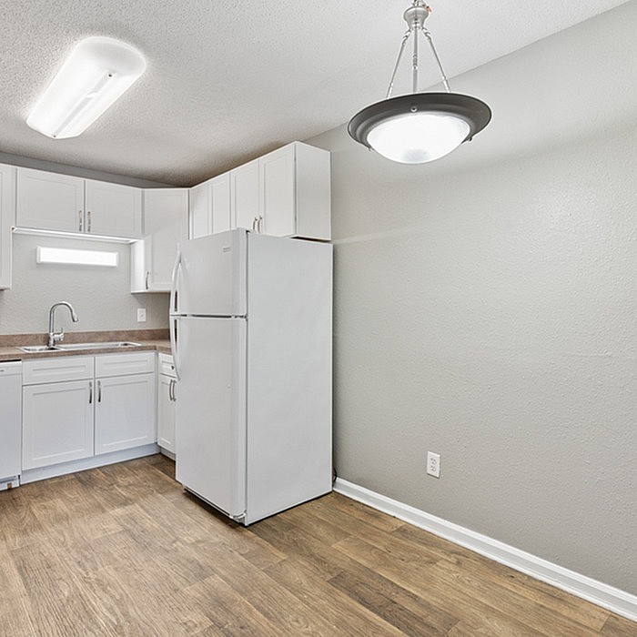 Chic apartment kitchen with modern white cabinetry, sleek countertops, and stylish lighting.
