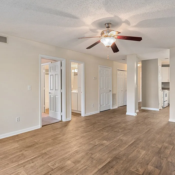 Inviting open-plan apartment featuring elegant wood flooring, modern ceiling fan, and ample natural light.