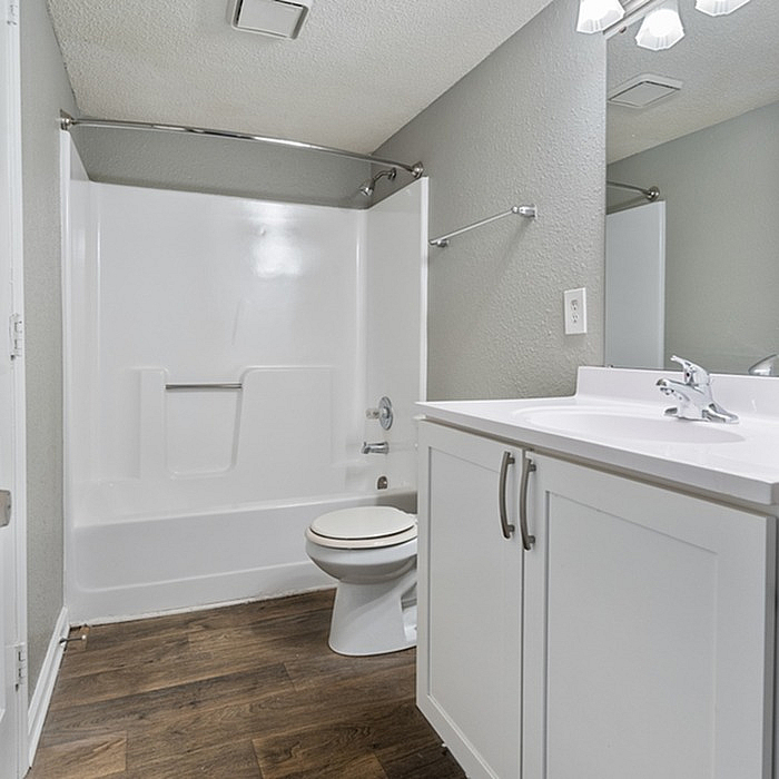 Modern bathroom with elegant cabinetry, sleek fixtures, and a pristine bathtub complemented by stylish wood flooring.