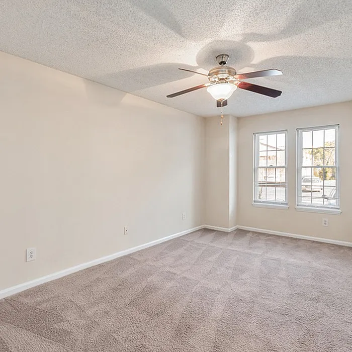 Inviting bedroom with plush carpeting, large windows for natural light, and a modern ceiling fan.