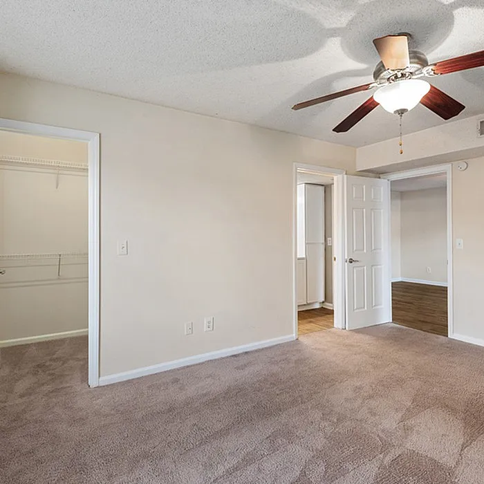 Inviting bedroom with plush carpet, ceiling fan, and a walk-in closet, perfect for a cozy and comfortable living space.