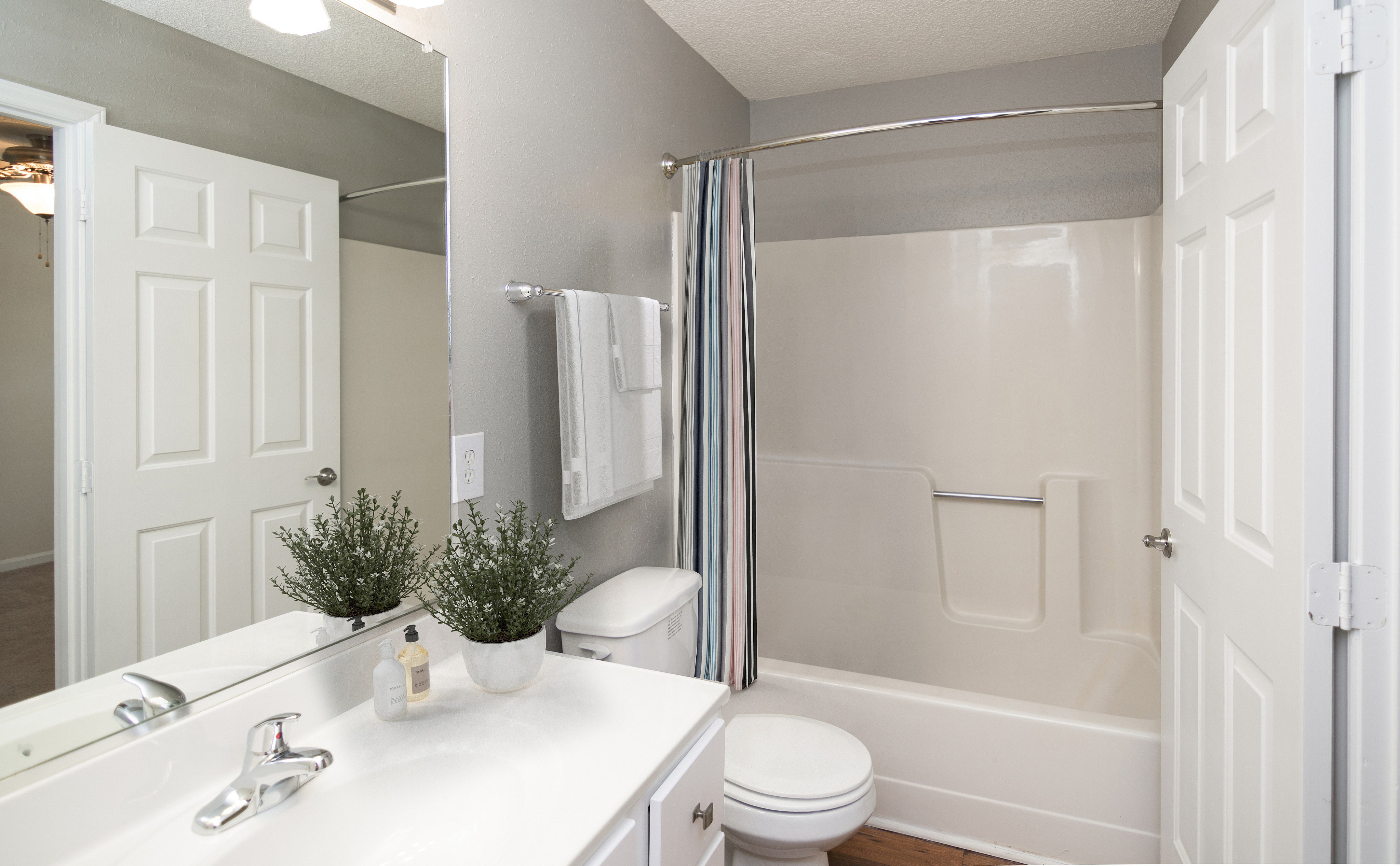 Bright and modern bathroom featuring elegant fixtures, pristine vanity with mirror, and a cozy shower-tub combo.