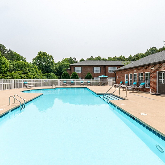 Inviting outdoor pool area with lounge chairs and scenic greenery, perfect for relaxation and summer enjoyment.