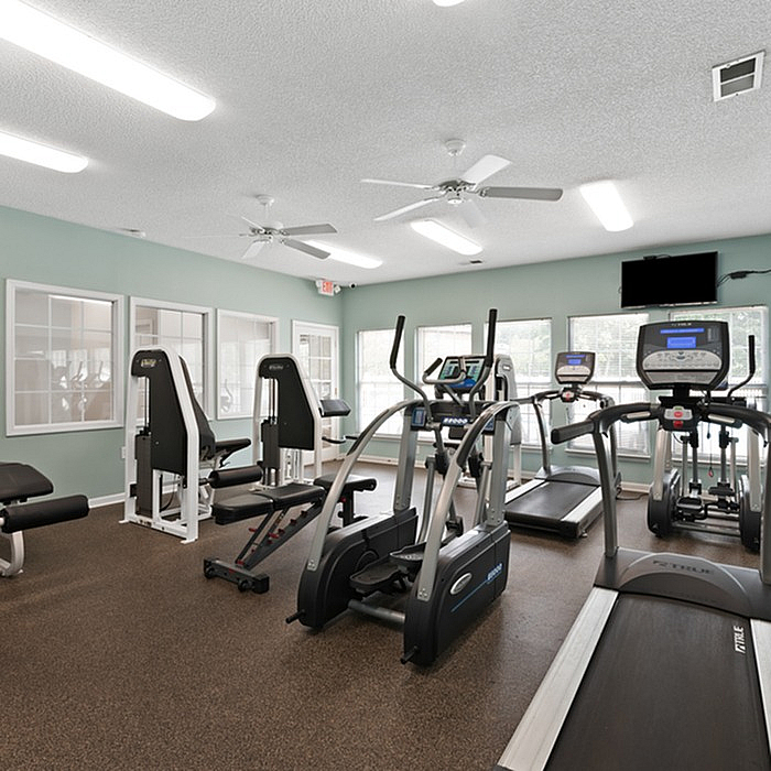 Inviting fitness center equipped with modern exercise machines, natural light, and vibrant ambiance for an energizing workout experience.